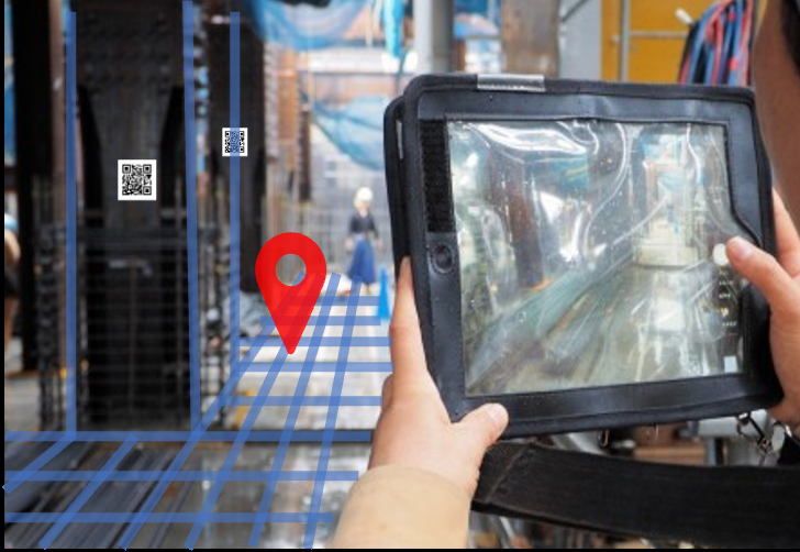 タブレット越しに建物内を見ると、赤いピンと青い床グリッドが実際の空間に重ねて表示されている様子